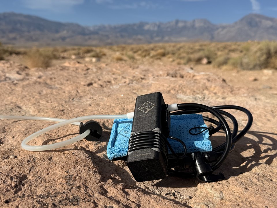 Geyser Clean Kit shower pump and accessories set out on a desert rock