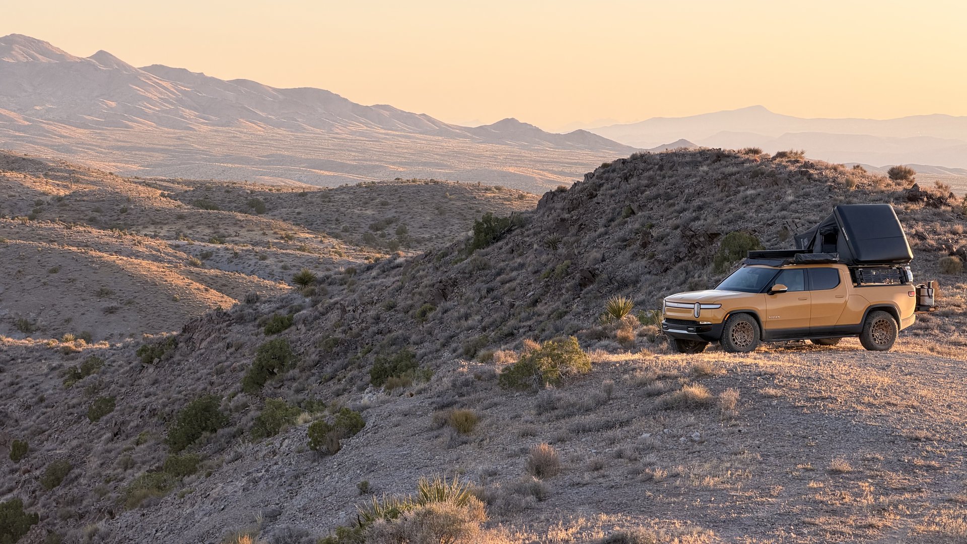 Compass Yellow Rivian R1T on a desert ridge at sunset